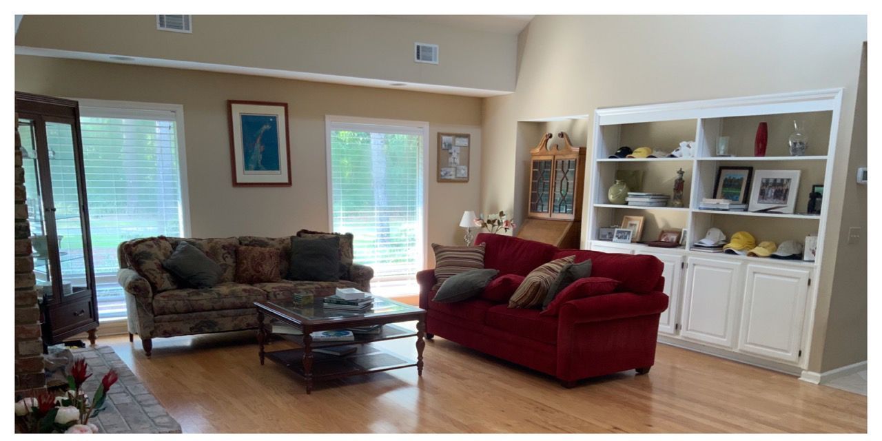 A living room with a red couch , two chairs , a coffee table and a bookshelf.
