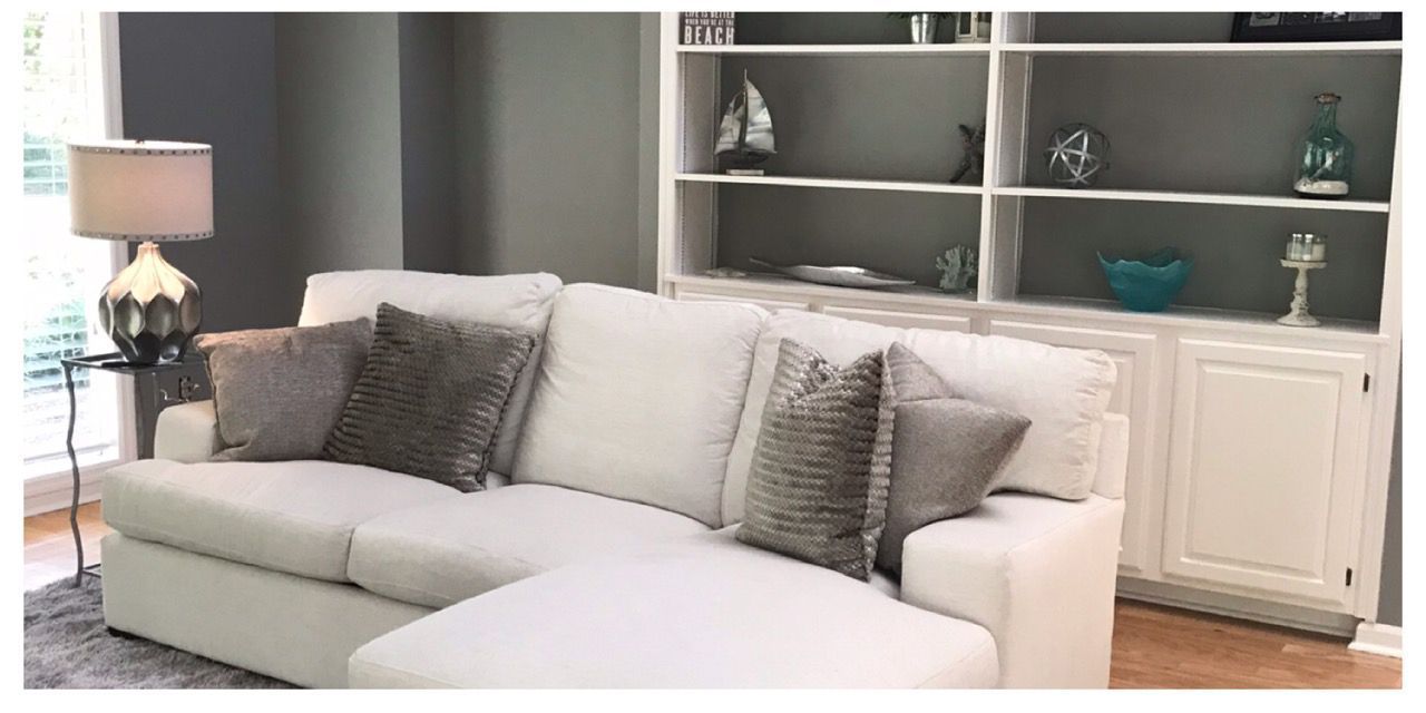 A living room with a white couch and a bookshelf.