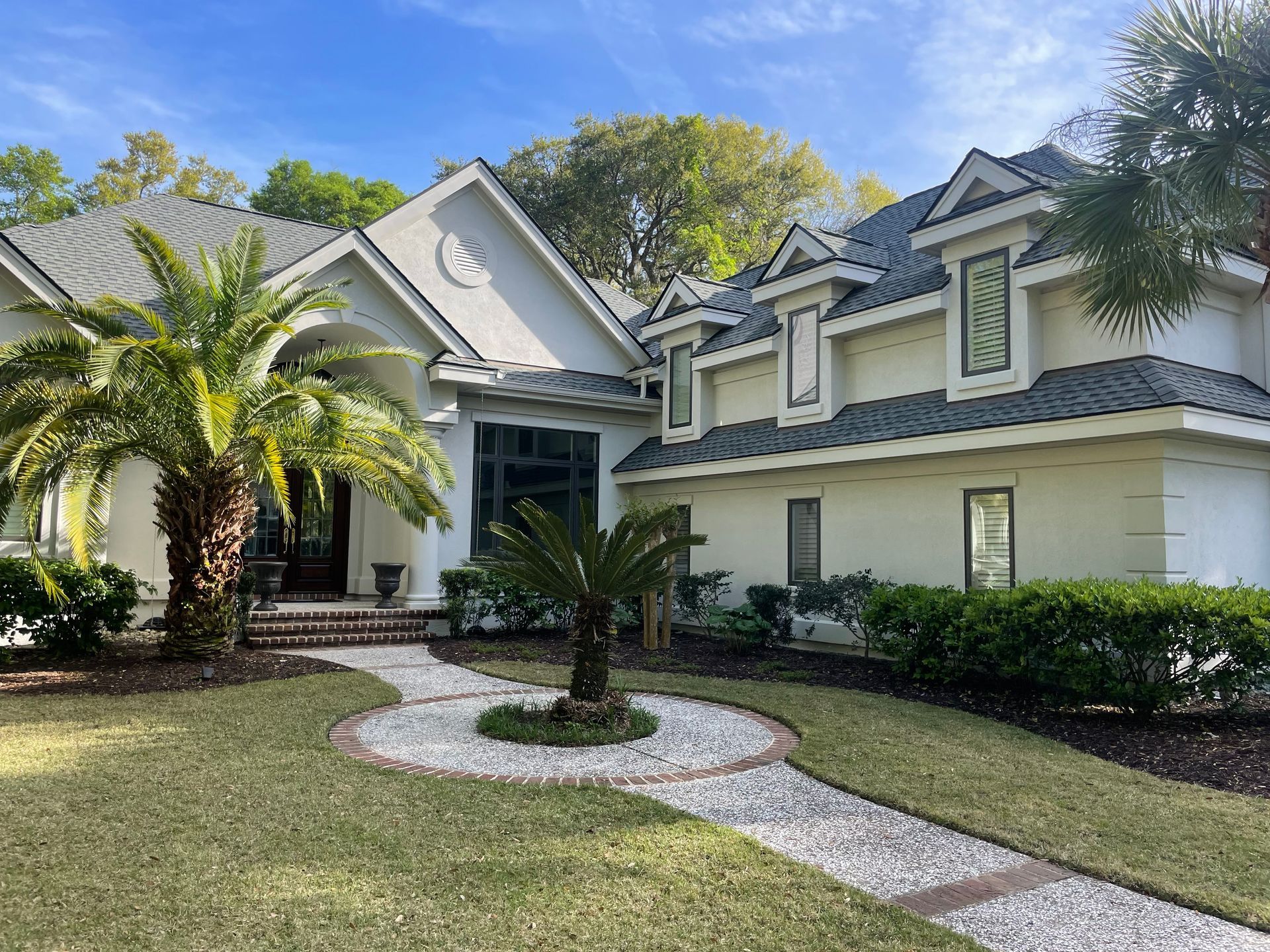A large white house with a palm tree in front of it.
