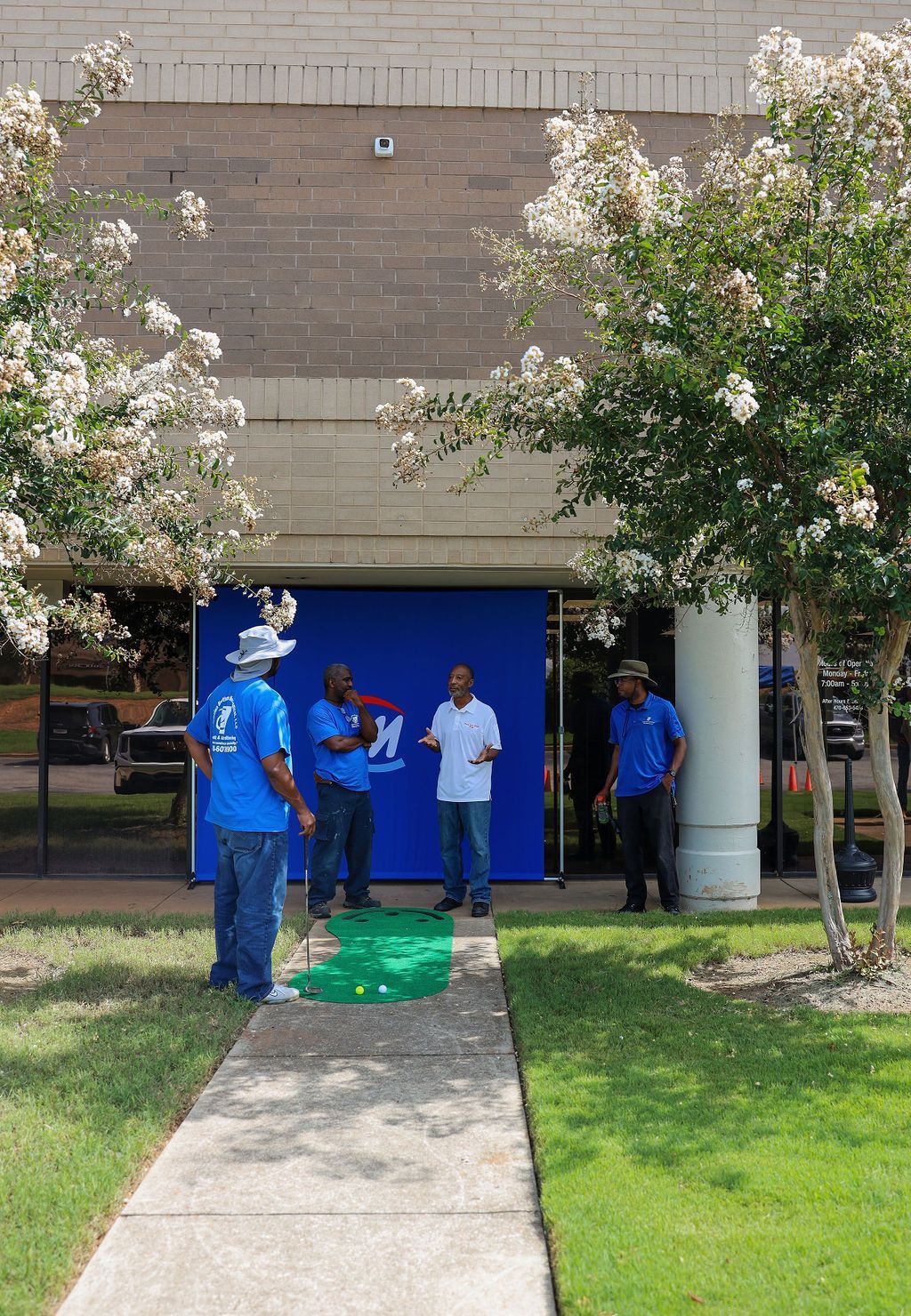 A group of men are standing on a sidewalk in front of a building.