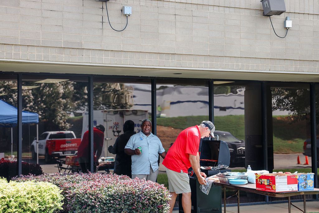 A man in a red shirt is working on a table outside of a building.