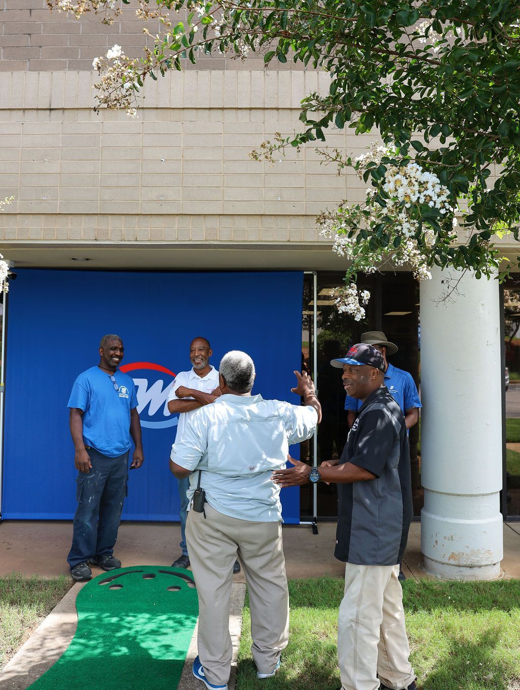 A group of men are standing in front of a building with a w on it