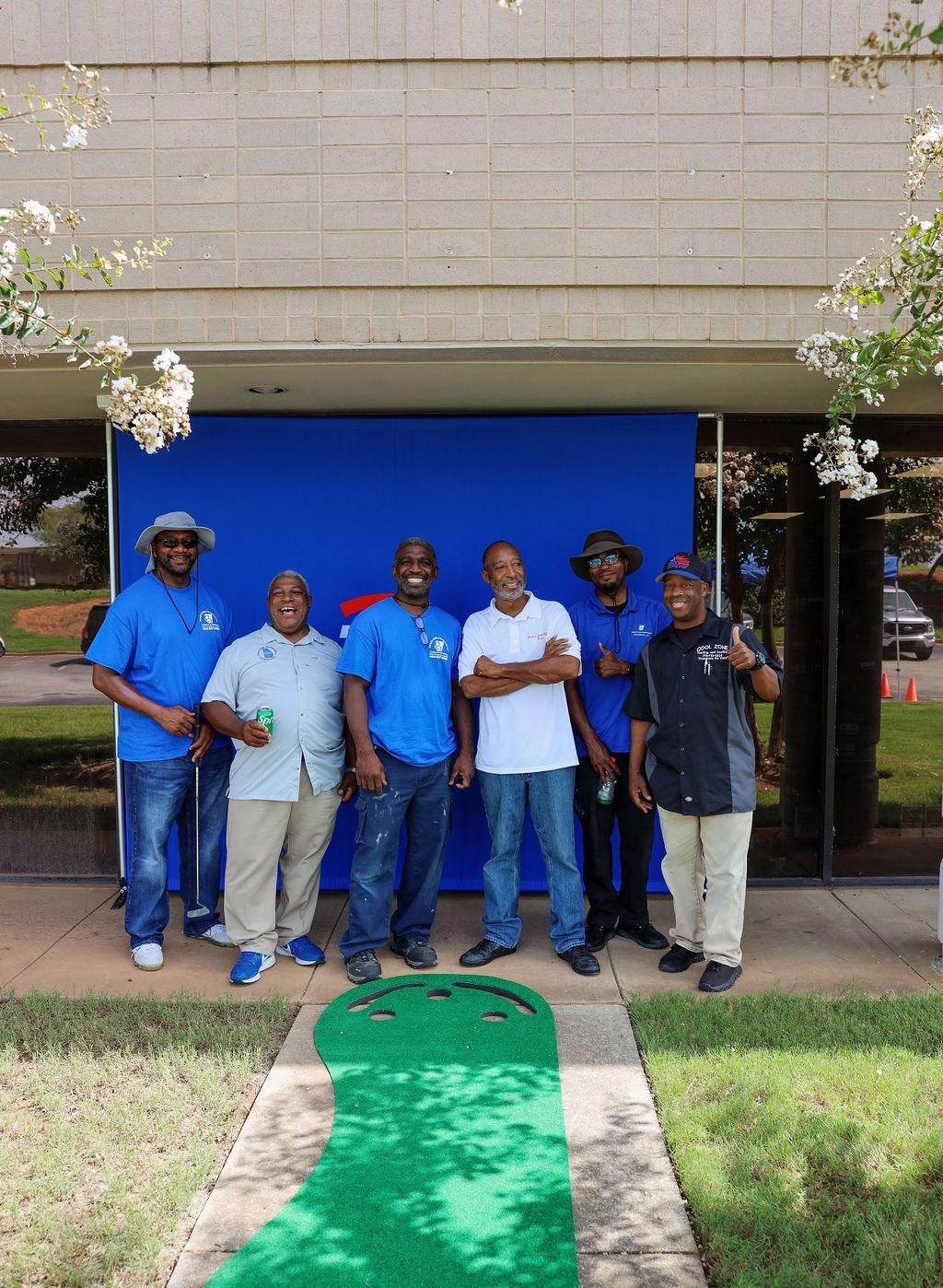 A group of men standing in front of a blue wall