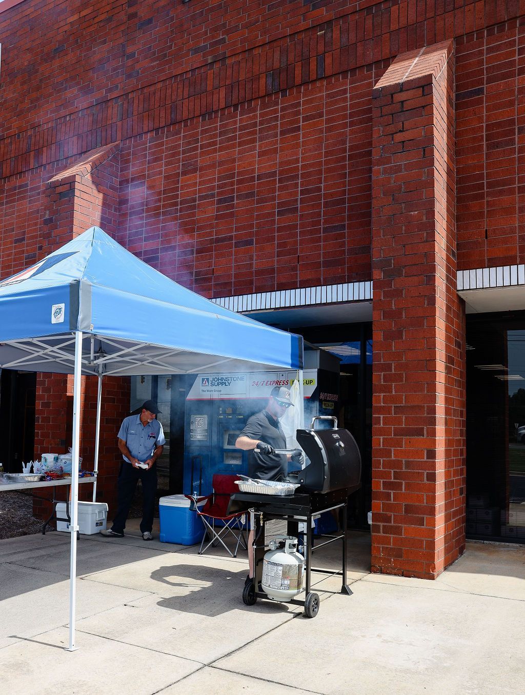 A man is grilling outside of a brick building