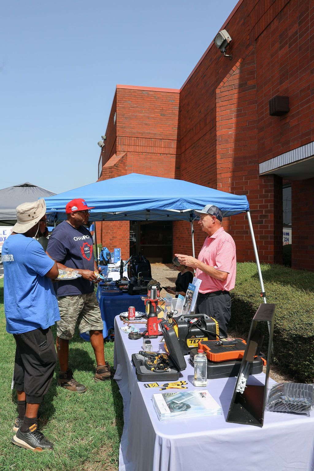 A group of men are standing around a table in front of a brick building.