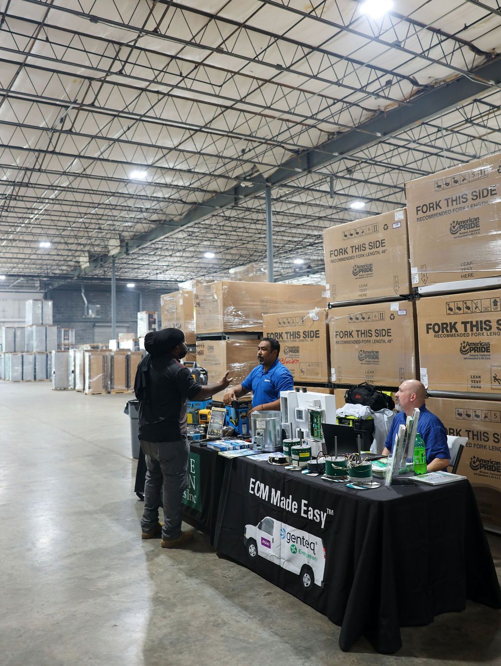 A group of people are standing around a table in a warehouse.