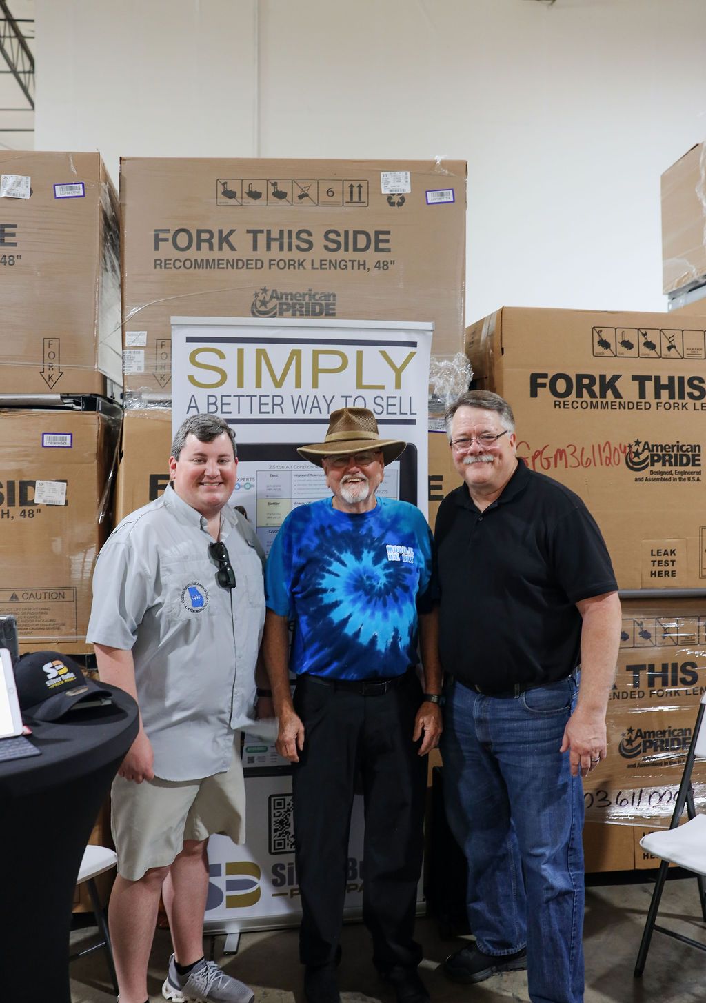 Three men are posing for a picture in front of a fork this side sign.