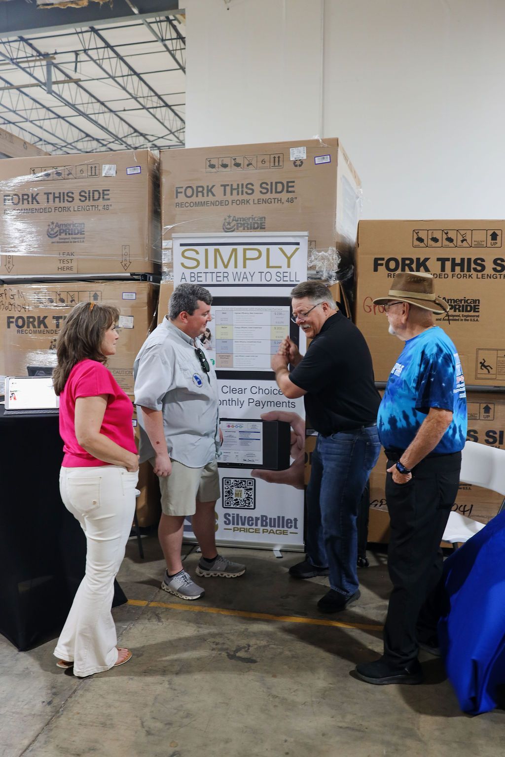 A group of people are standing around a stack of boxes in a warehouse.