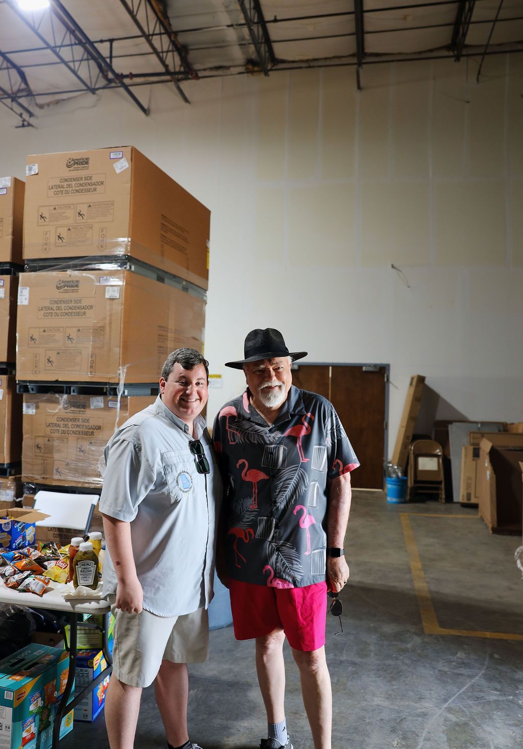 Two men are posing for a picture in a warehouse.