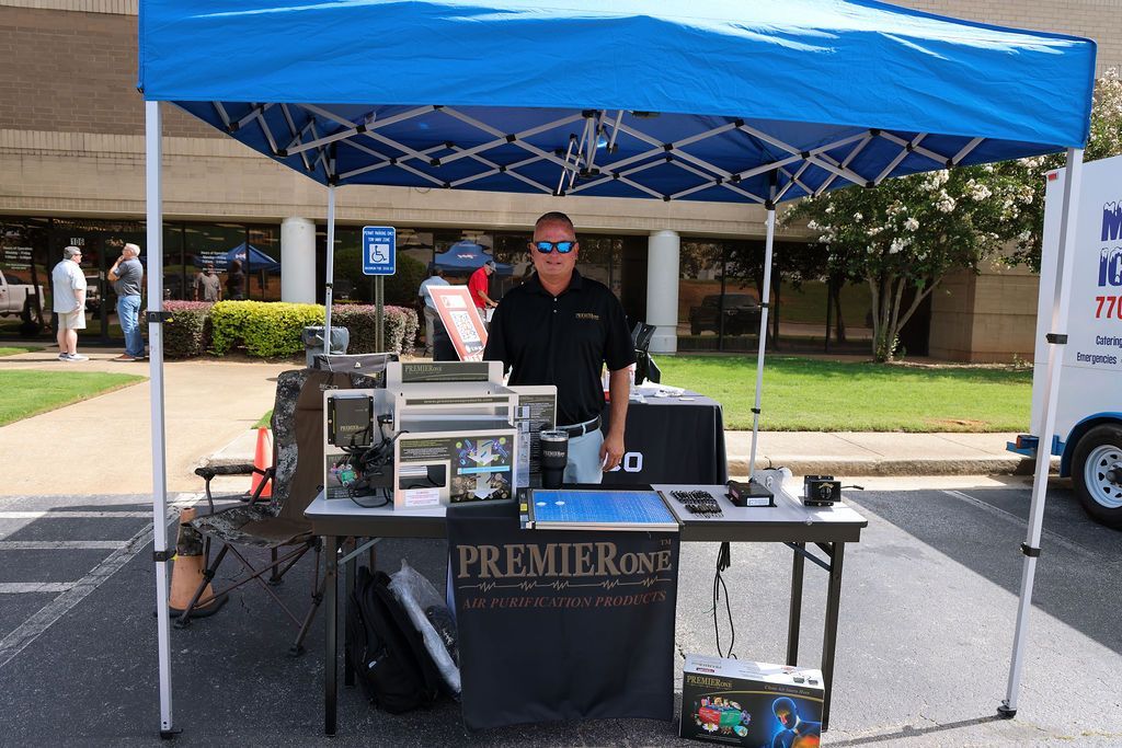 A man is standing behind a table under a blue tent.