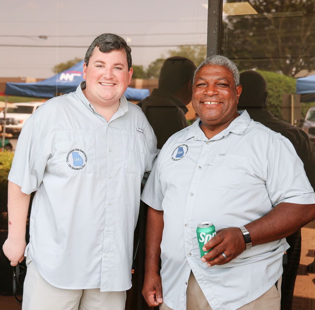 Two men are posing for a picture and one is holding a can of sprite