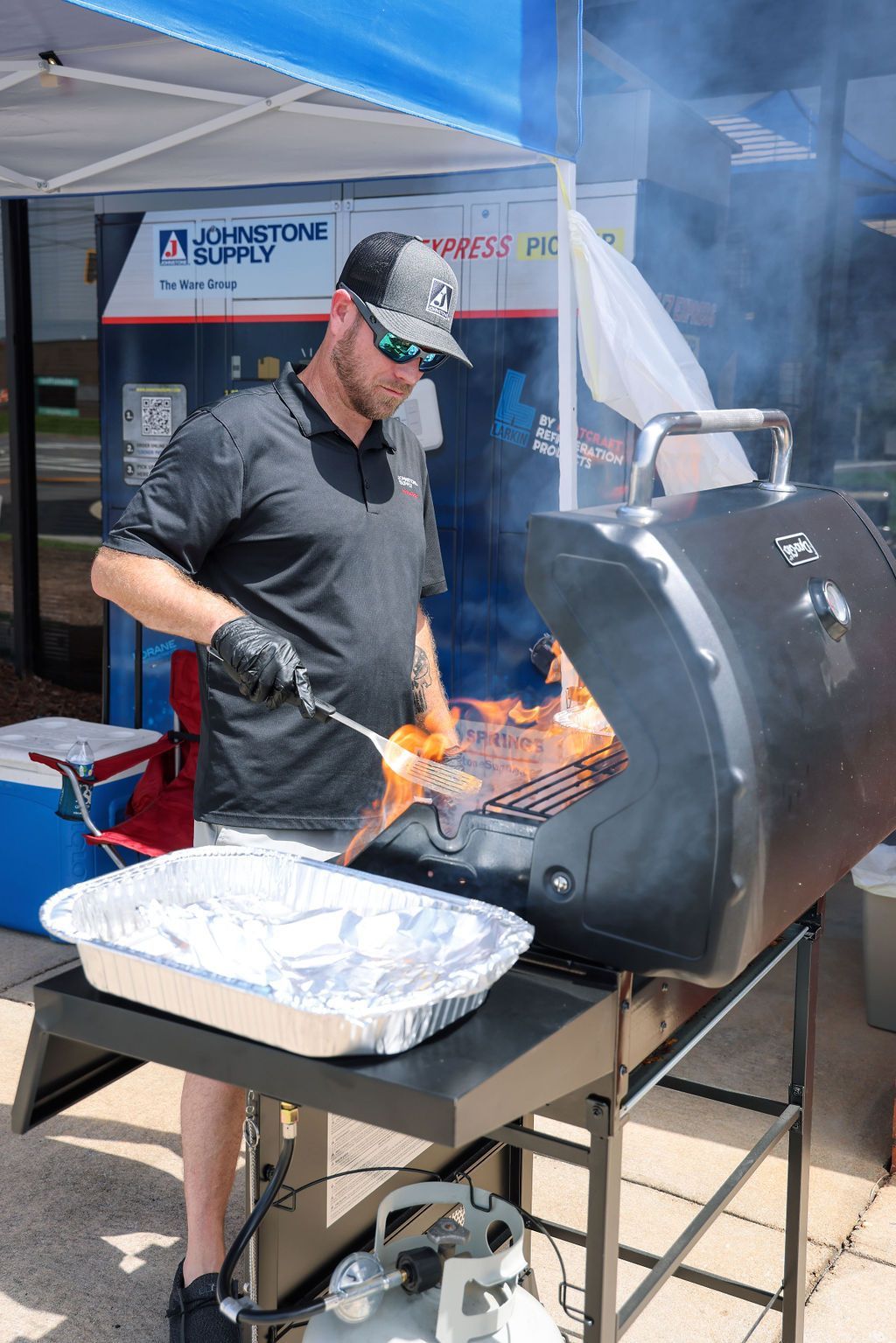 A man is cooking food on a grill under a tent.