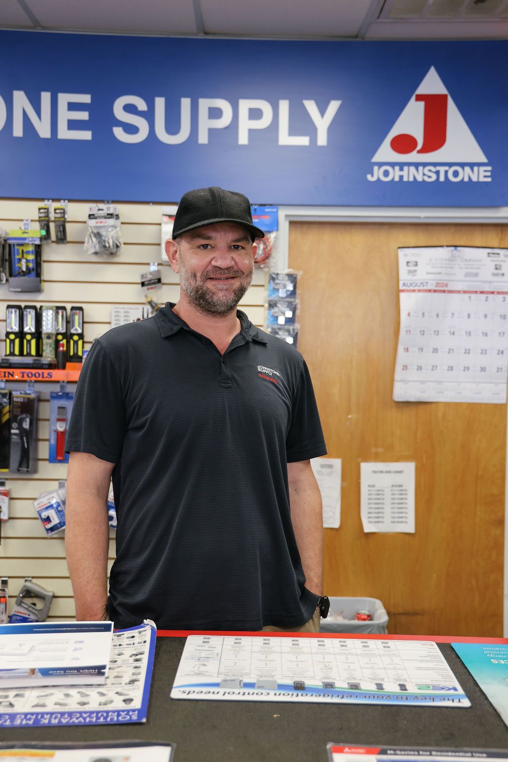 A man is standing behind a counter in a johnstone store.