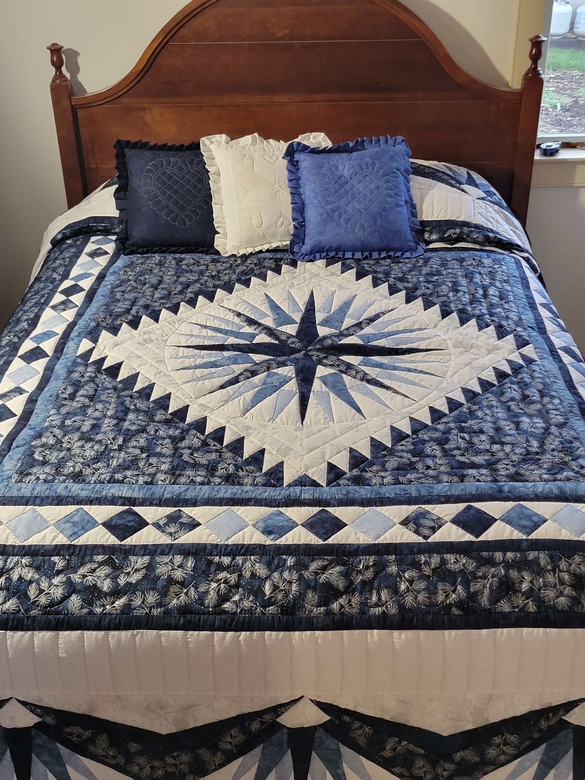 A bed with a purple and white quilt on it