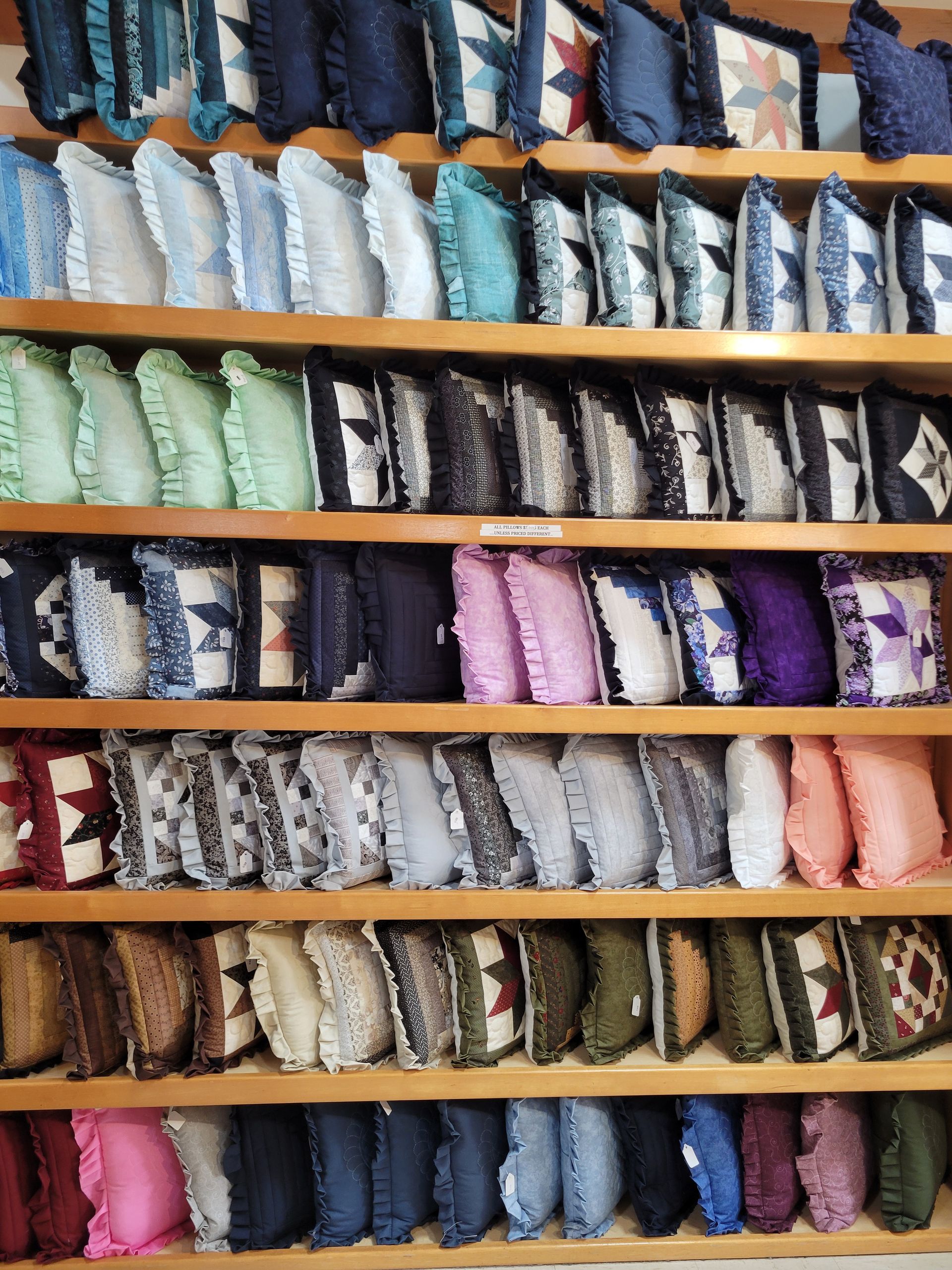 A shelf filled with lots of pillows with pictures on them.
