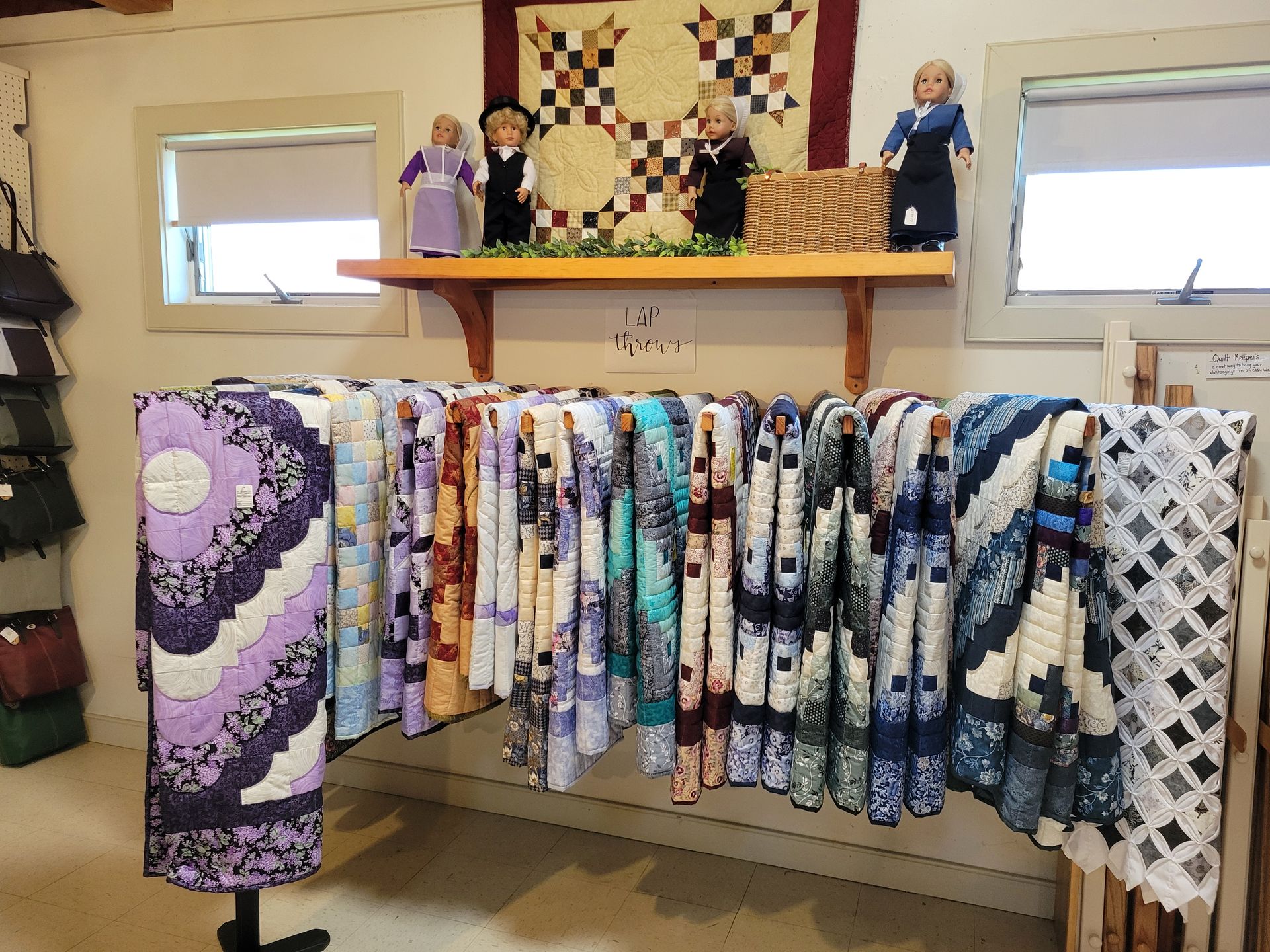 A shelf filled with quilts and a sign that says be still