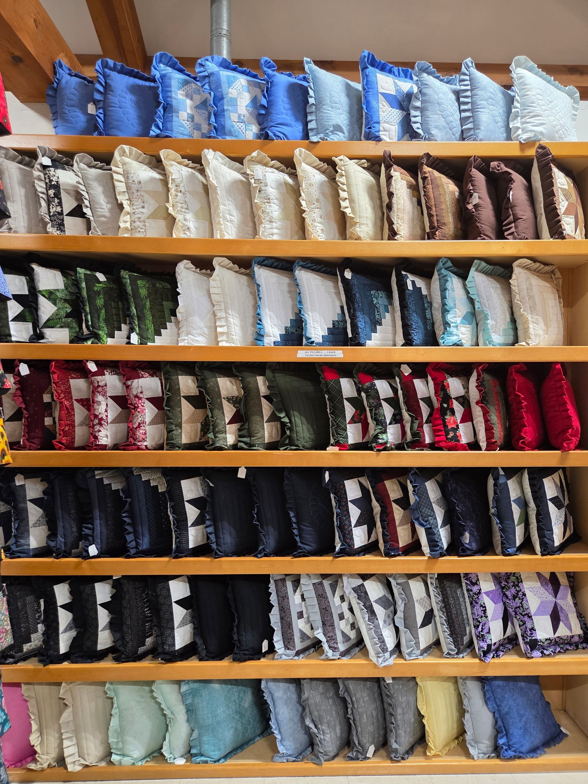 A shelf filled with lots of pillows with pictures on them.