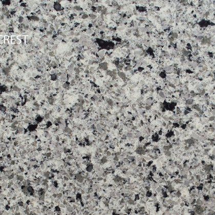 A close up of a white granite counter top with black spots.
