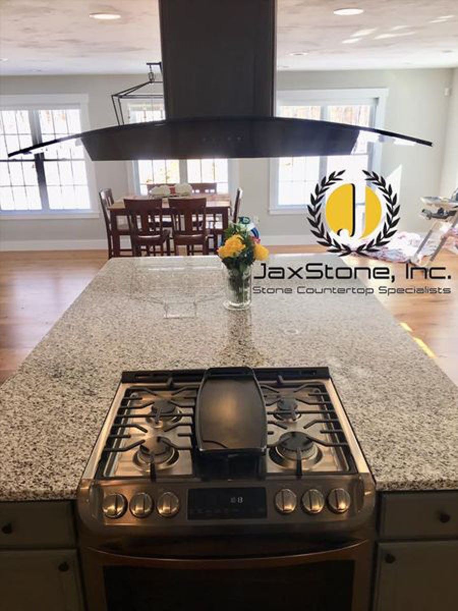 A stove top oven is sitting on top of a granite counter top in a kitchen.