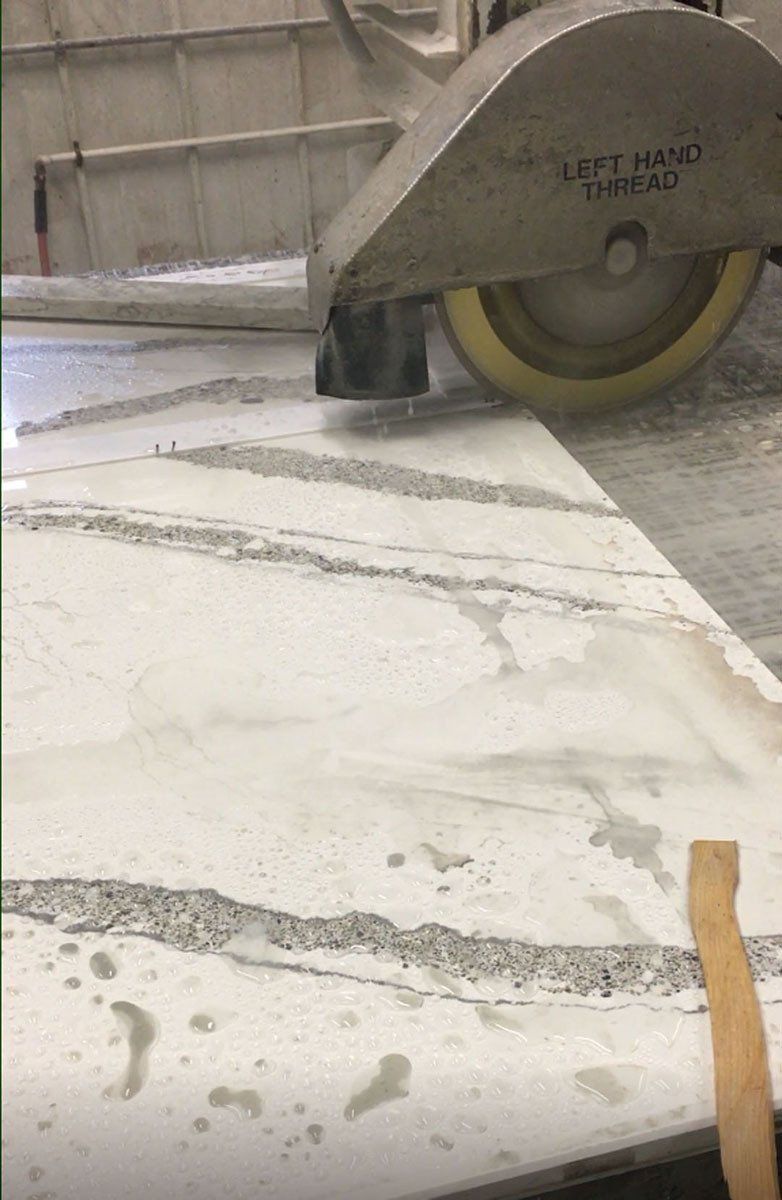 A machine is cutting a piece of marble on a table.