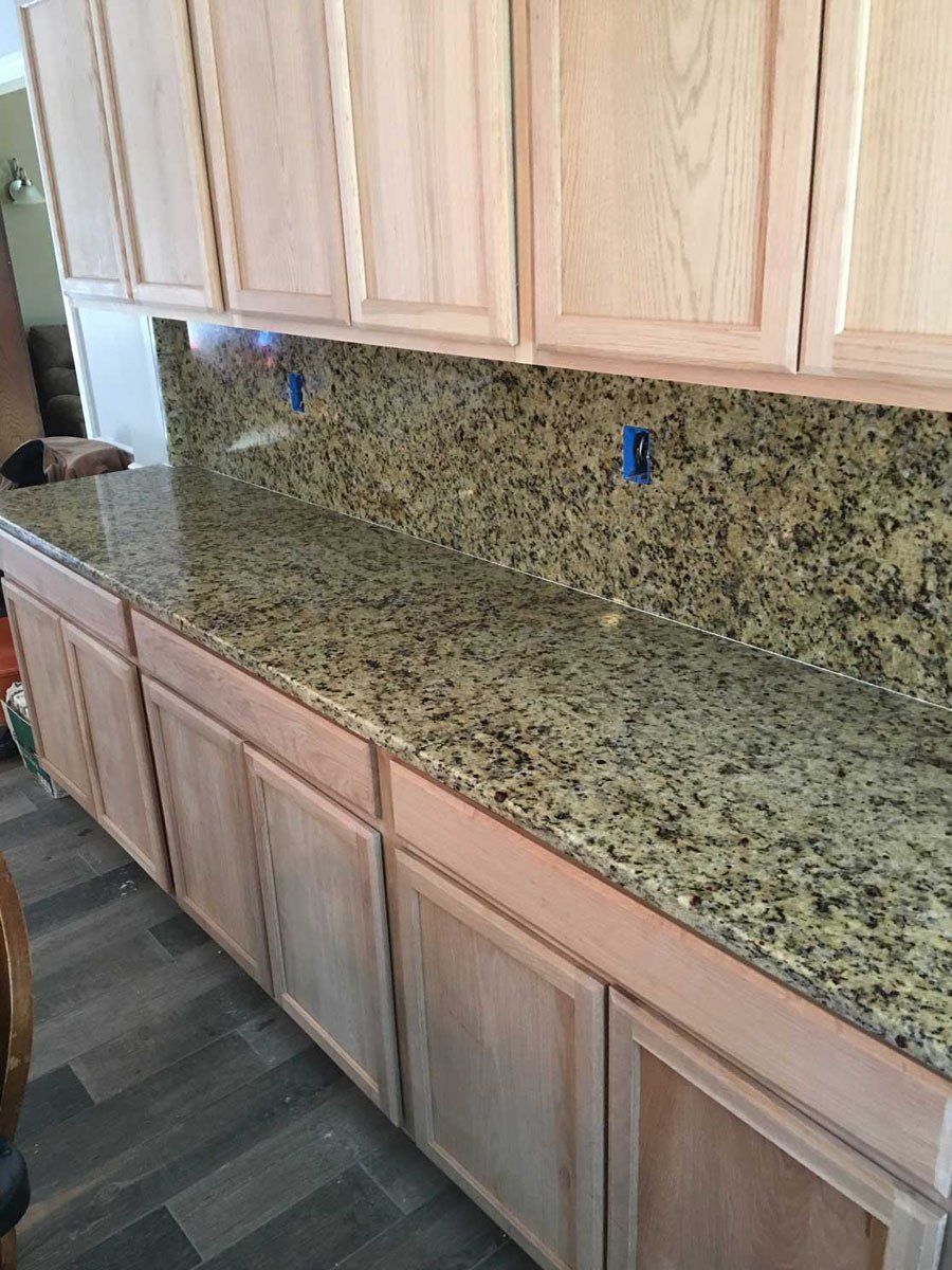 A kitchen with granite counter tops and wooden cabinets.