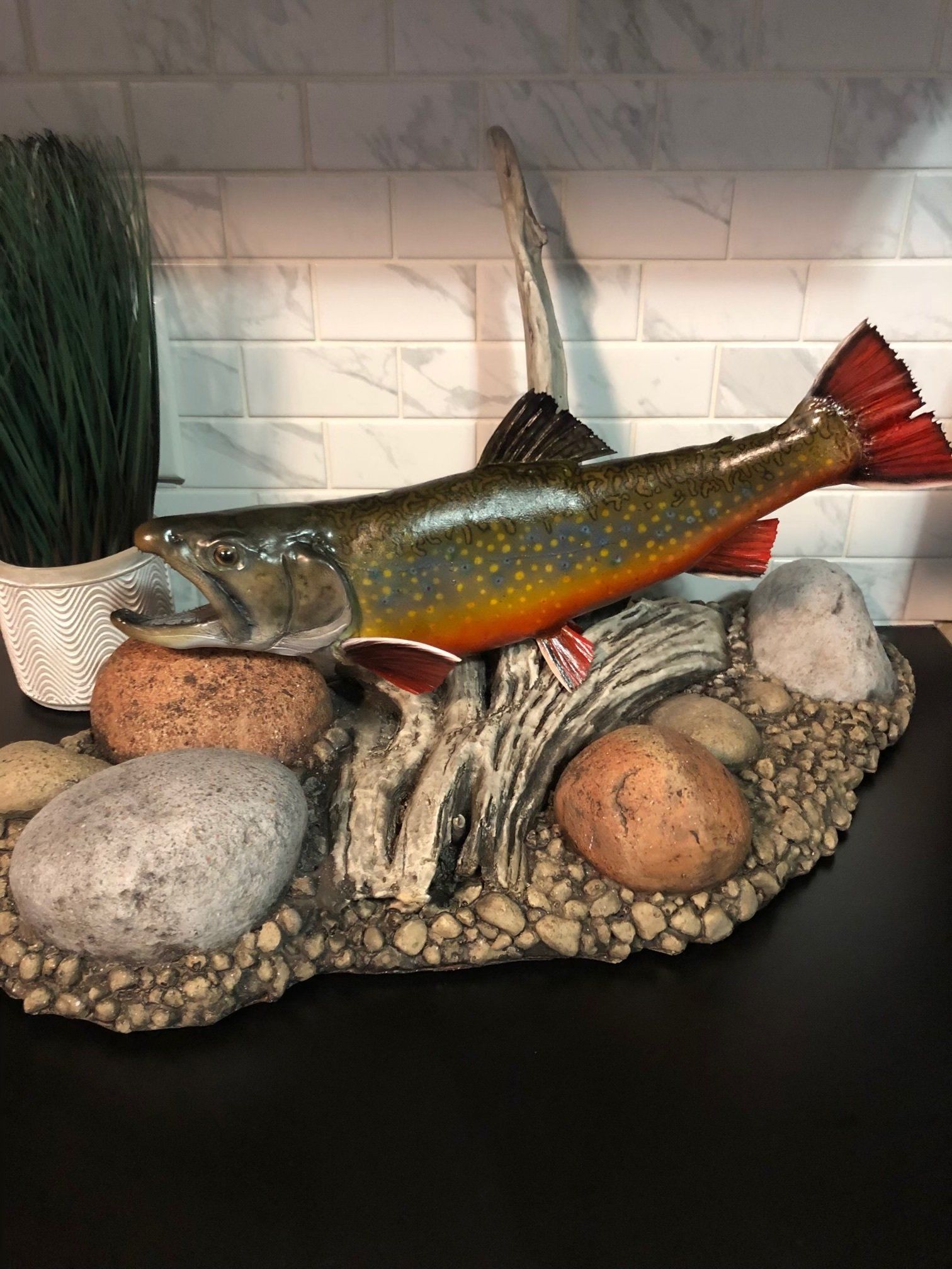 A fish is sitting on top of a rocky surface on a table.