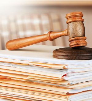 A wooden judge 's gavel is sitting on top of a stack of papers.