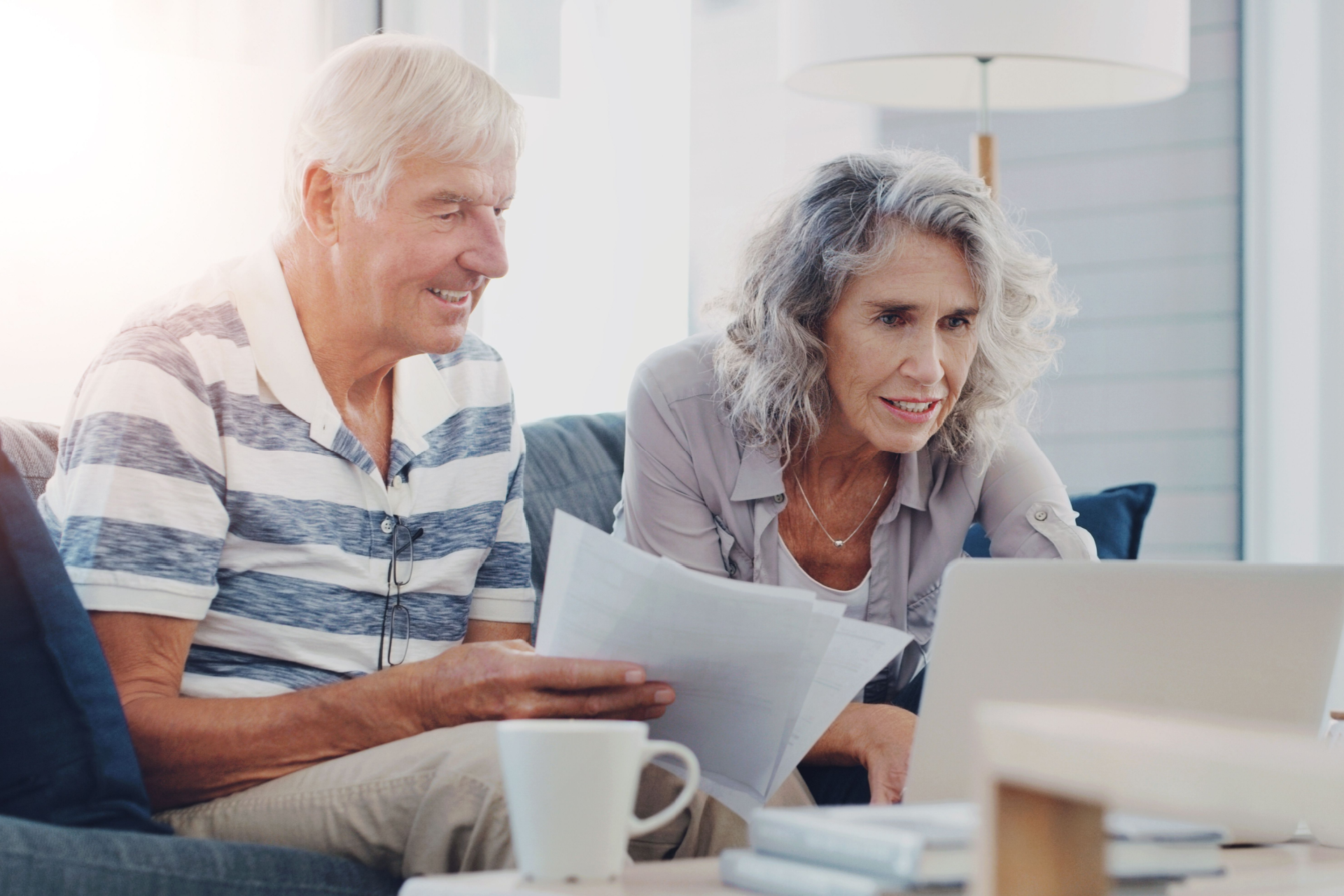 A man and a woman are sitting on a couch looking at a laptop computer.