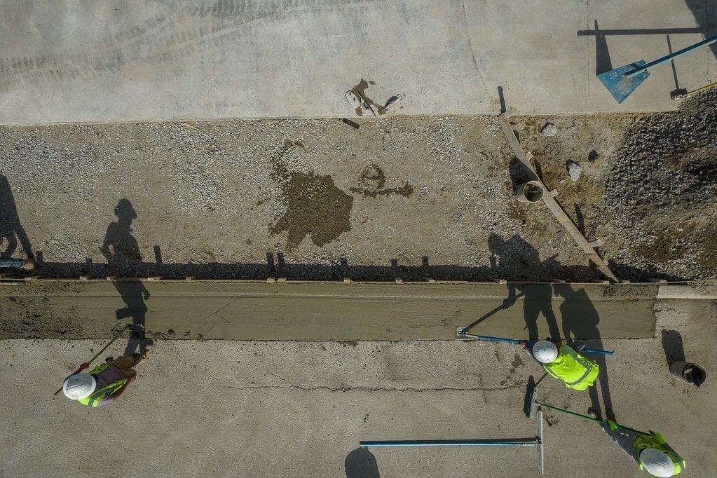 Workers in neon safety vests clearing debris from a roadside ditch.