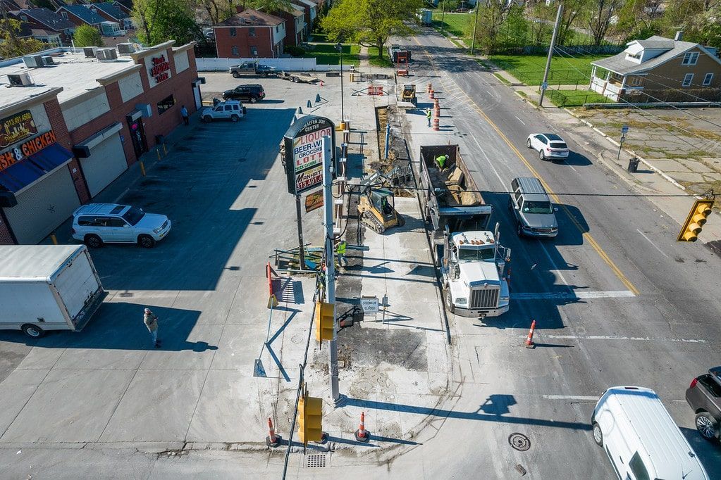 Aerial view of a street intersection with cars, parked vehicles, and buildings on a sunny day
