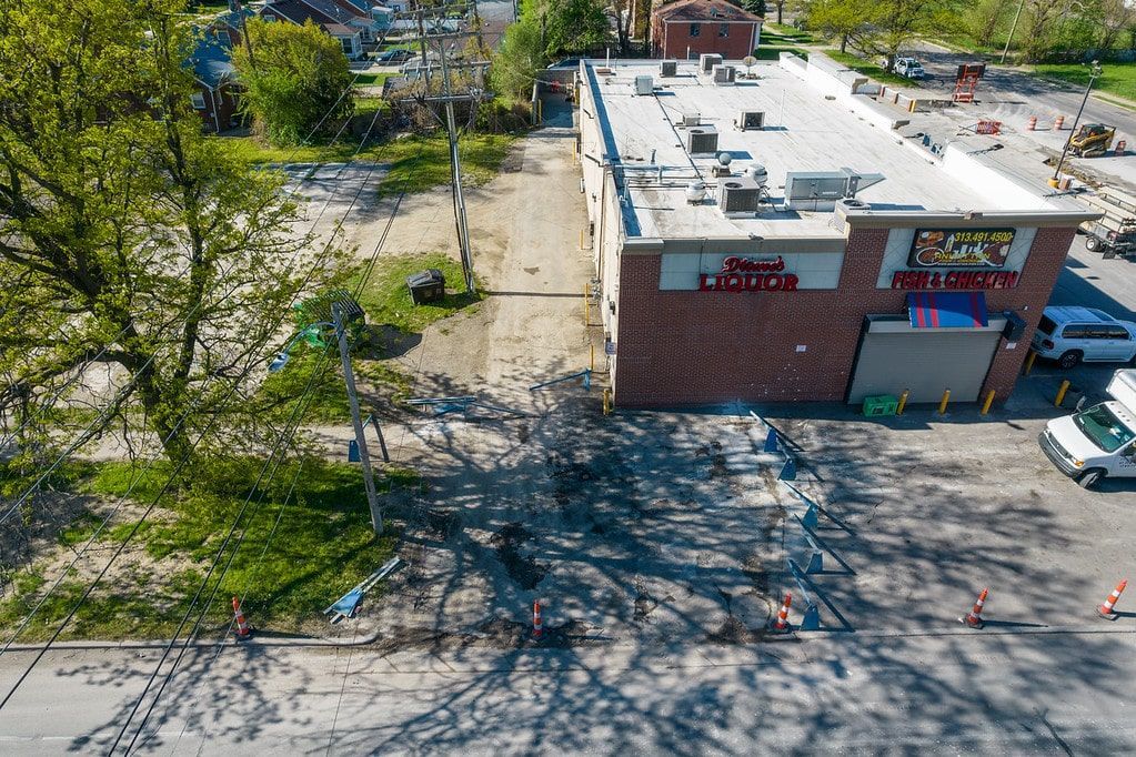 Aerial view of a brick building beside a tree-lined parking lot and road