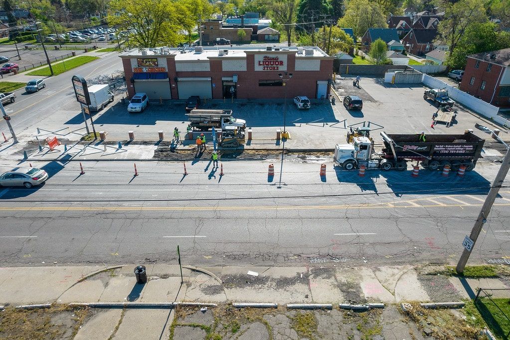 Aerial view of a brick building and sidewalk with people walking along a street in front