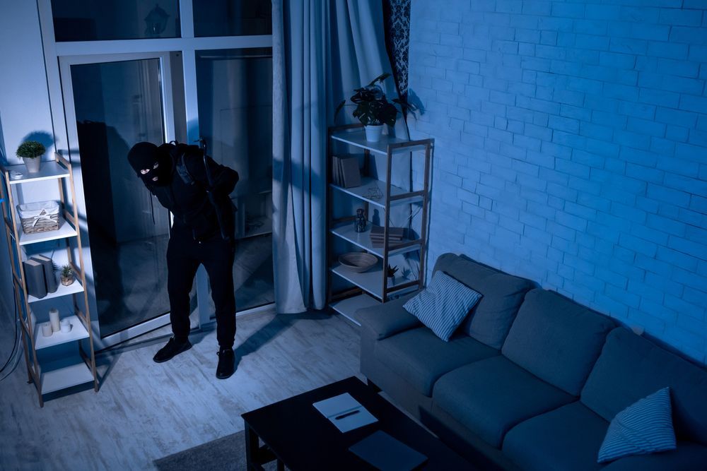 A man in a mask is standing in a living room at night.