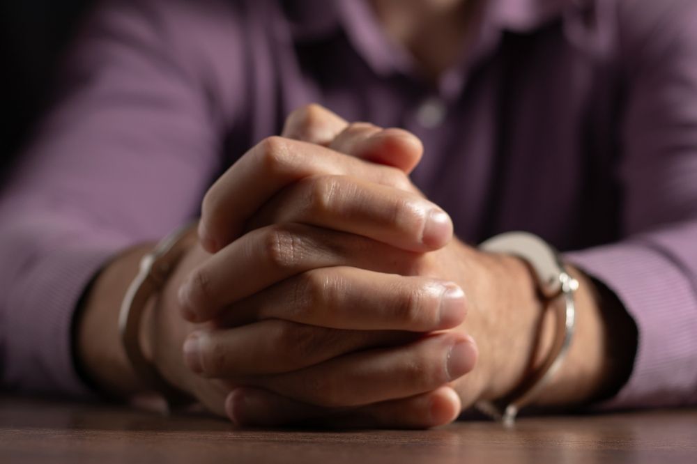 A man is sitting at a table with handcuffs