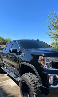 A black truck is parked in a parking lot on a sunny day.