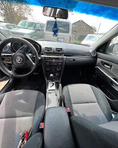 The interior of a car with a steering wheel and a rear view mirror.