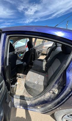 The back seat of a blue car with the door open.