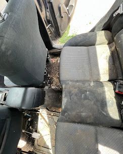 A dirty car seat is sitting in the trunk of a car.