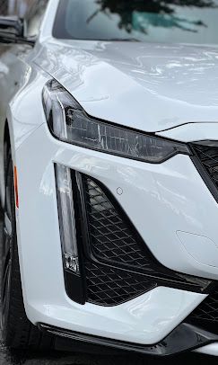 A close up of a white car parked on the side of the road.