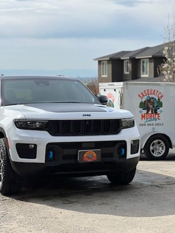 A white jeep is parked next to a white trailer.