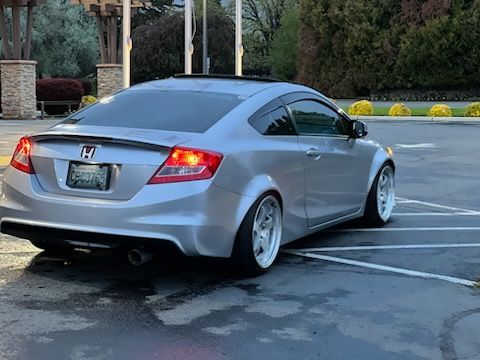 A silver honda civic coupe is parked in a parking lot.