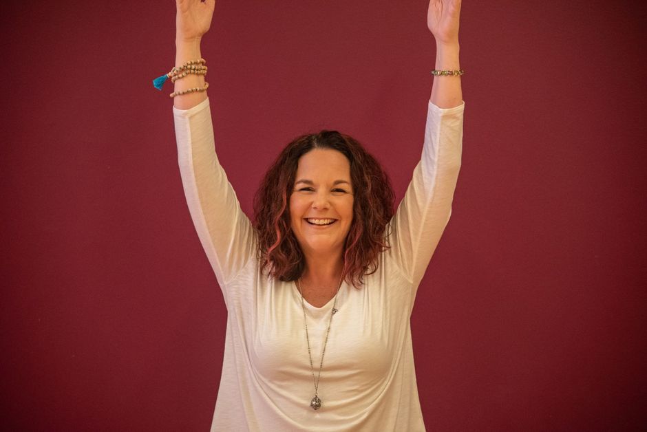 A woman in a white shirt is raising her arms in the air.