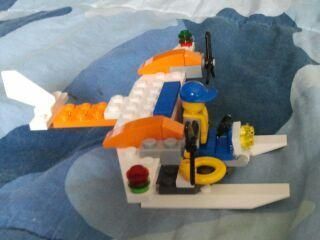A lego airplane is sitting on a bed