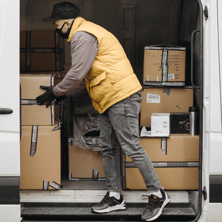 A man in a yellow vest is loading boxes into a van.