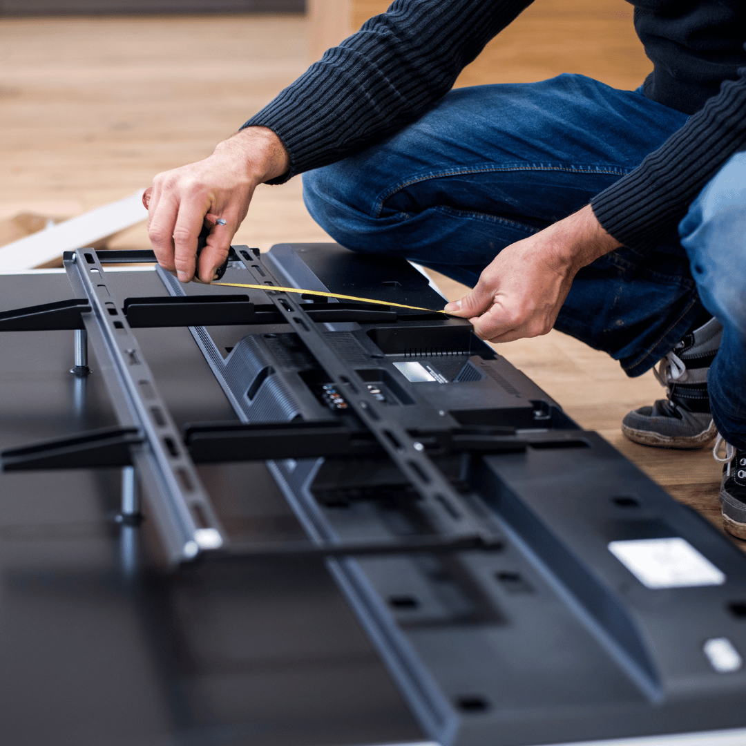 A man is measuring a tv with a tape measure