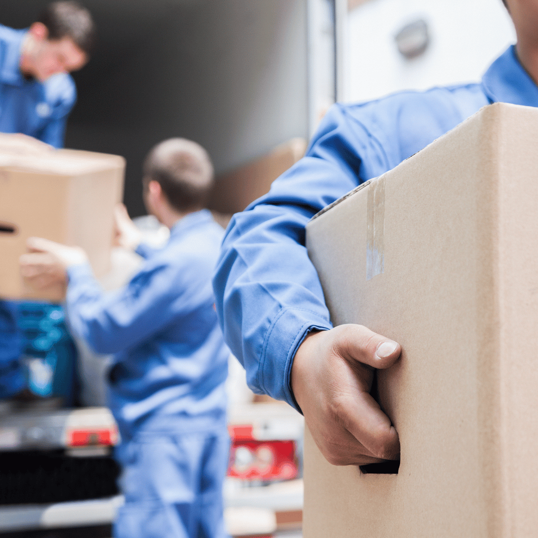 A man in a blue shirt is holding a cardboard box