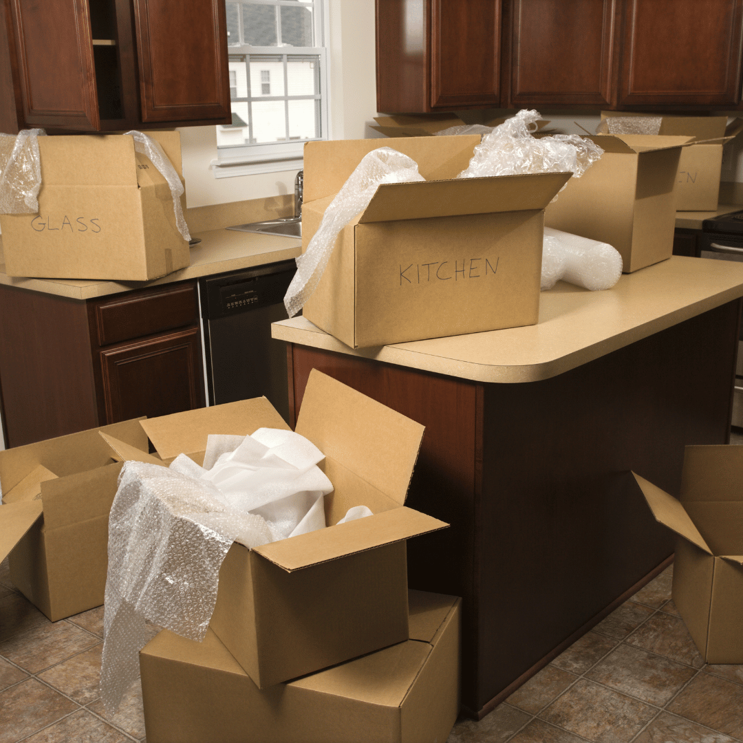 Many cardboard boxes are stacked on top of each other in a kitchen