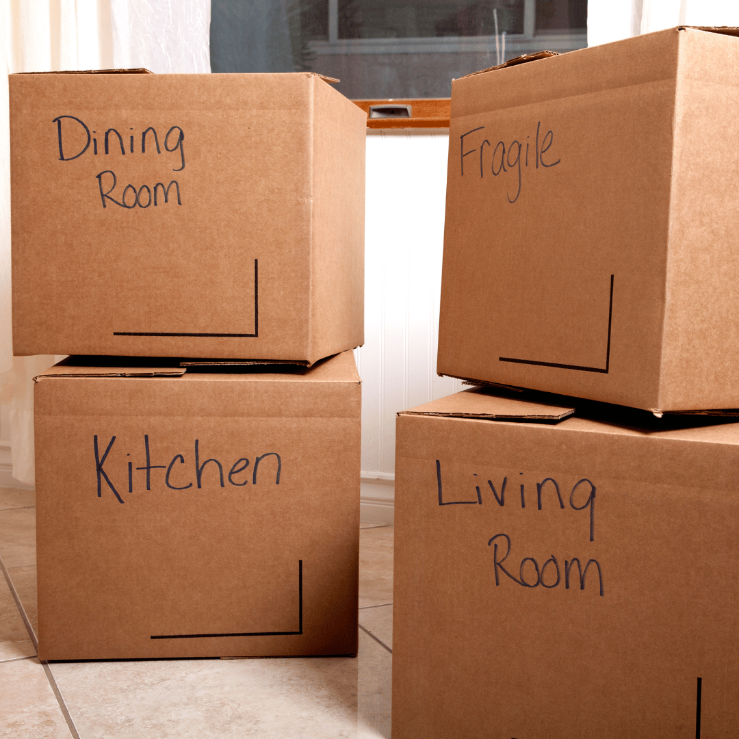 Four cardboard boxes labeled dining room kitchen and living room are stacked on top of each other