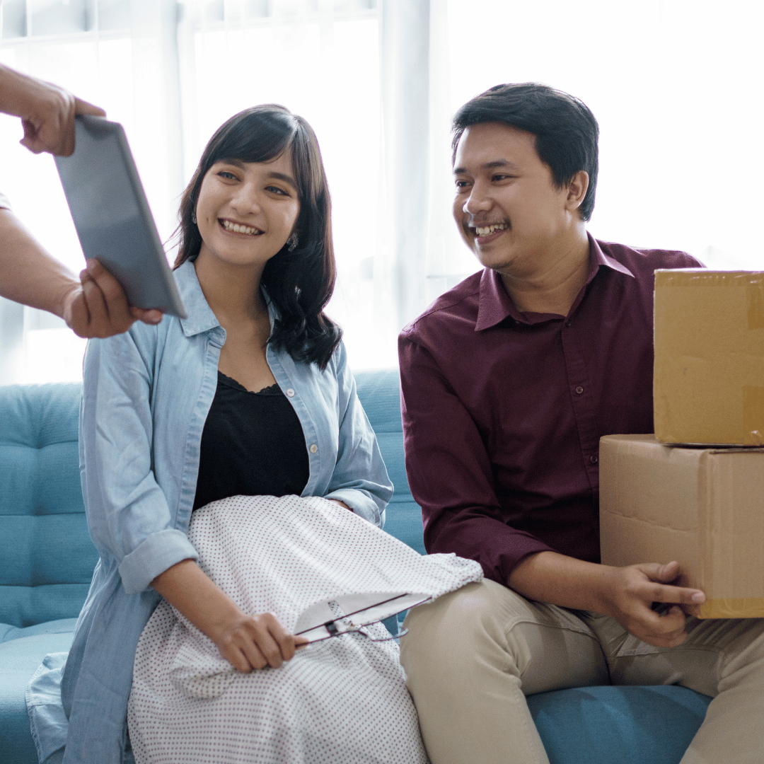 A man and a woman are sitting on a couch looking at a tablet.