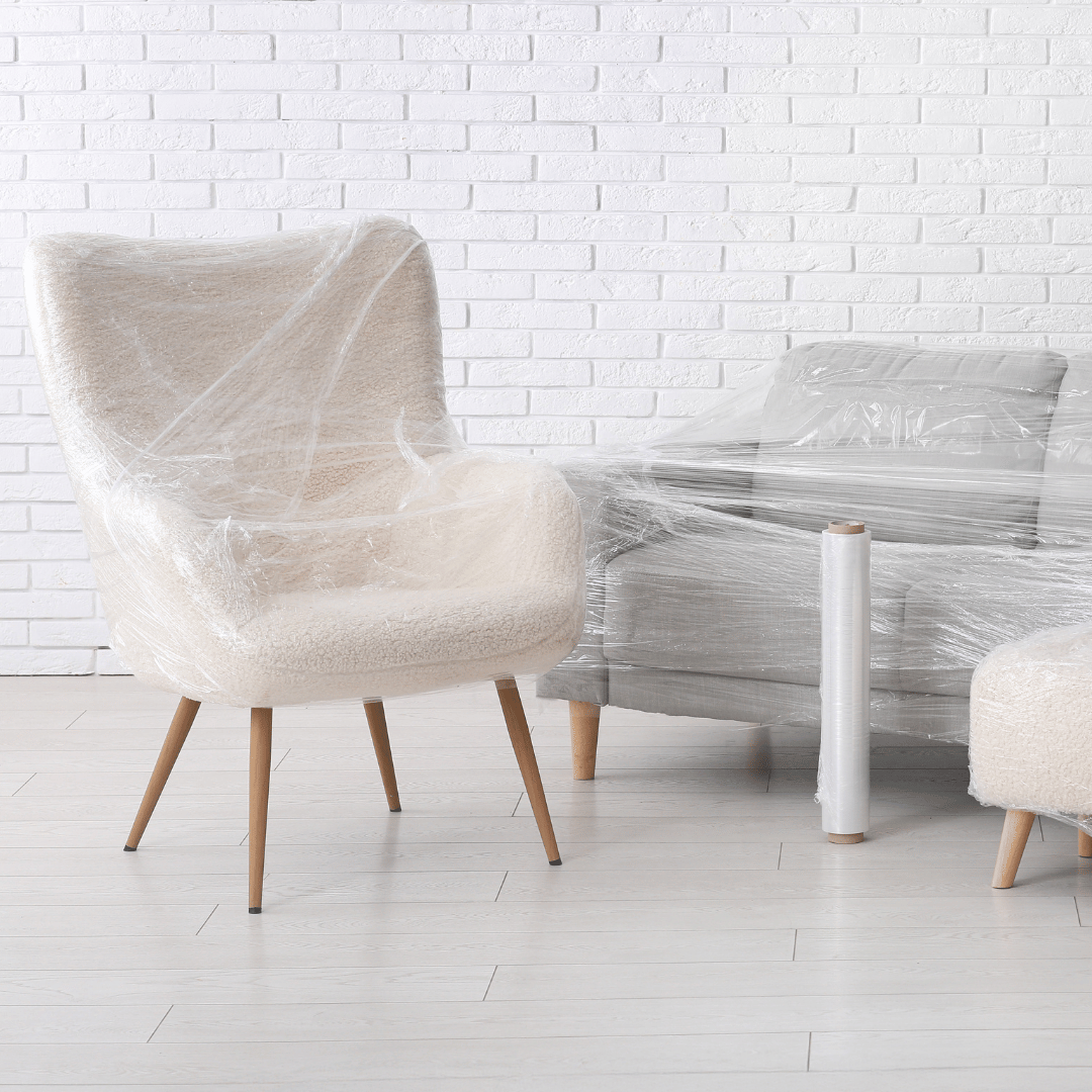 A chair and a couch are wrapped in plastic.